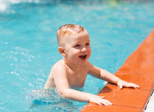 Portrait of happy little boy swimming in pool Portrait of happy little Caucasian boy swimming in outdoor pool and smiling. Summer vacation, sport, health and childhood concept